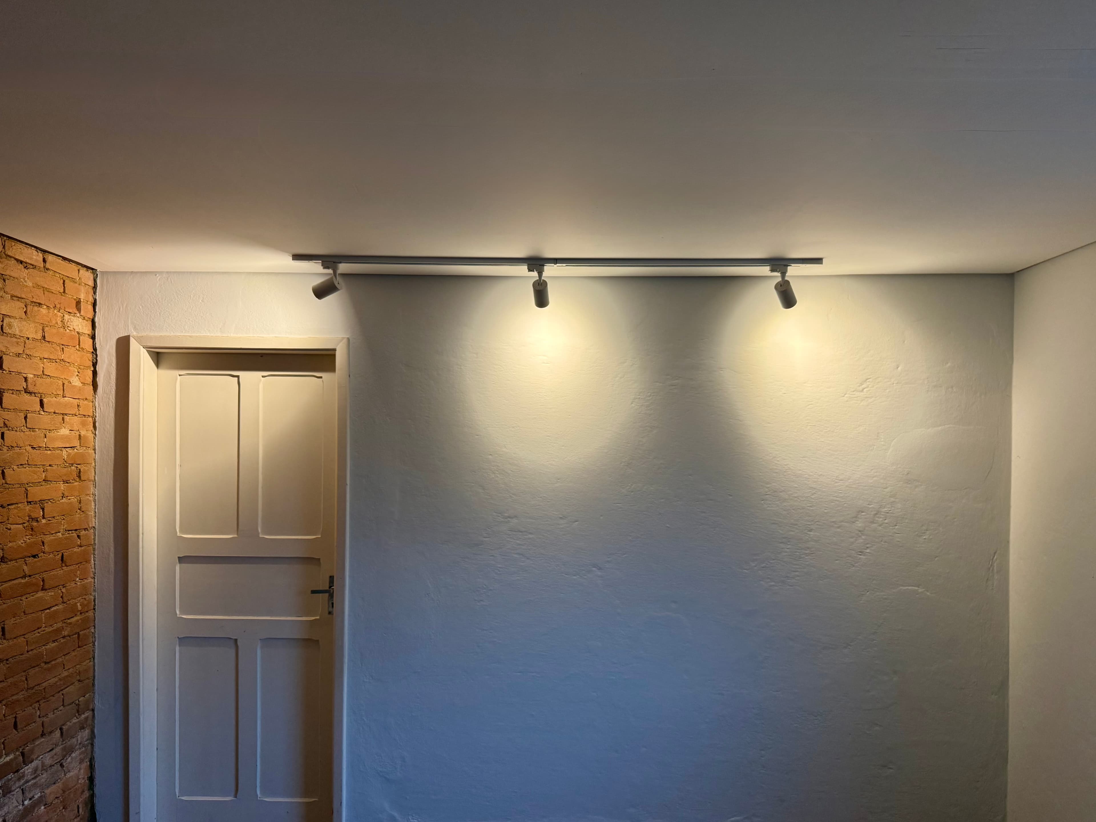 Forro de drywall acabado e pintado, com trilho de três spots iluminando a parede, em residência em Mogi das Cruzes.