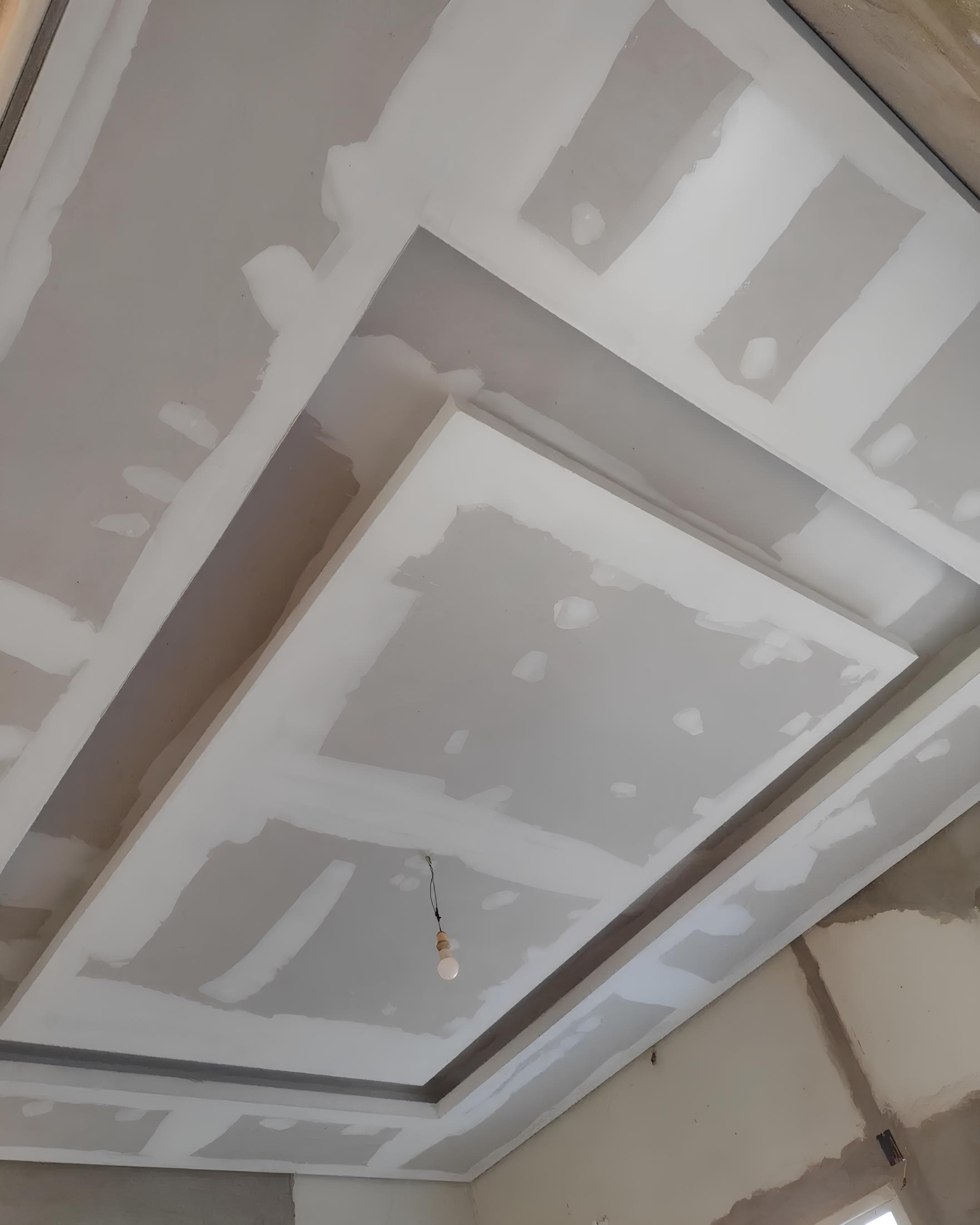 Forro de drywall com sanca rebaixada e ponto de luz pendente no centro do teto.